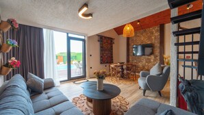 Una sala de estar moderna con un sofá, una mesa de centro redonda y una pared de acento de piedra.
