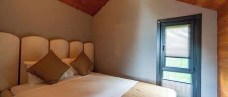 Un dormitorio con techo de madera, una ventana con persianas y una cama con almohadas.