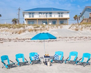 A beachfront property with a two-story building, a sandy beach with lounge chairs, and a blue umbrella. - Beachfront Estate | 2 Homes, Private Access, Sleeps 22 (St. Augustine)