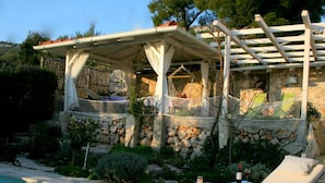 A poolside area with a lounge chair, a pergola, and a stone wall. - Apartments Mediterraneo Blues (Sibenik)