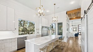 Een moderne keuken met een groot eiland, barkrukken en hanglampen.