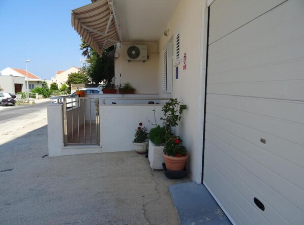 A residential garage with a white door, a small entryway with a metal gate, and potted plants outside. - Lumina Sea Apartments Cavtat (Konavle)
