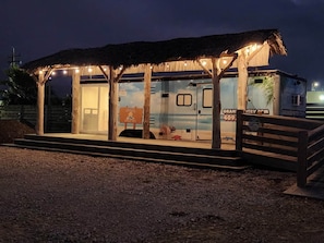 Een strandtent met rieten dak, houten palen en een klein zitgedeelte.