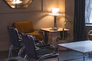Ein modernes Zimmer mit Sofa, Stühlen, einem Tisch, einer Lampe und einem Blumentopf.