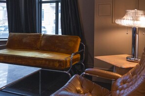 Ein modernes Zimmer mit einer Couch, einem Sessel, einem kleinen Tisch und einer Lampe.