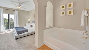 A bedroom with a large bed, a bathtub, and a balcony with curtains. - Upstay Modern 2BR Condo Near Disney (Winter Garden)