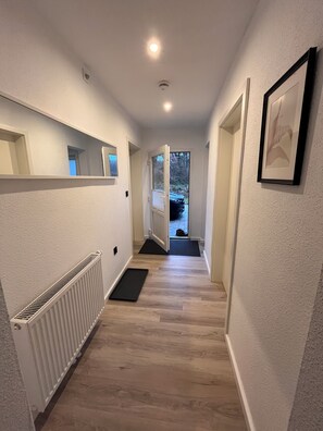 A hallway with a radiator, a door leading outside, and a framed picture on the wall.