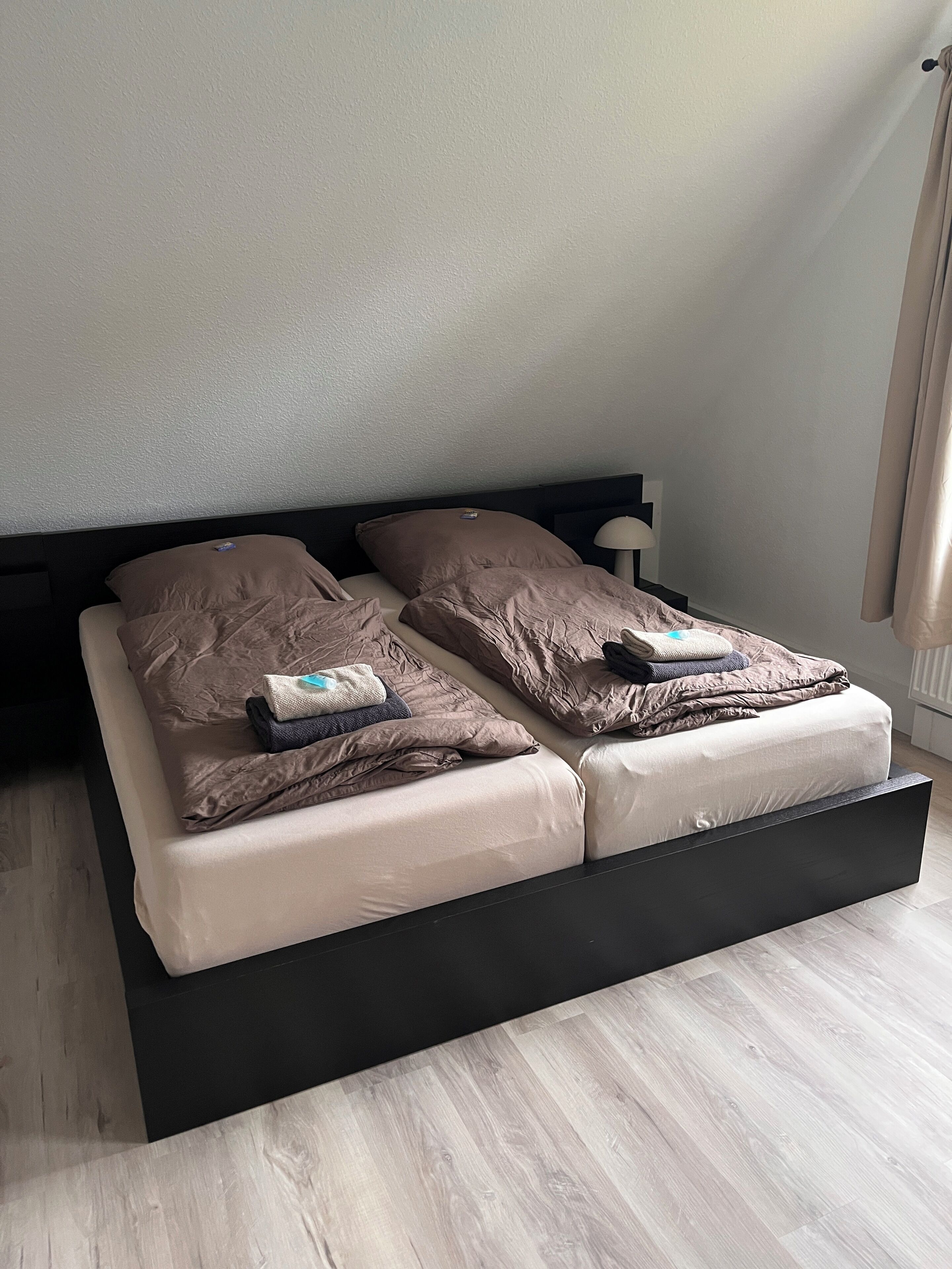 A bed with a black frame, two pillows, and a blanket.