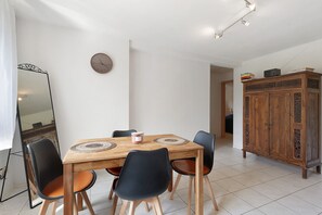 Un coin repas avec une table en bois, des chaises noires, une horloge et un buffet.