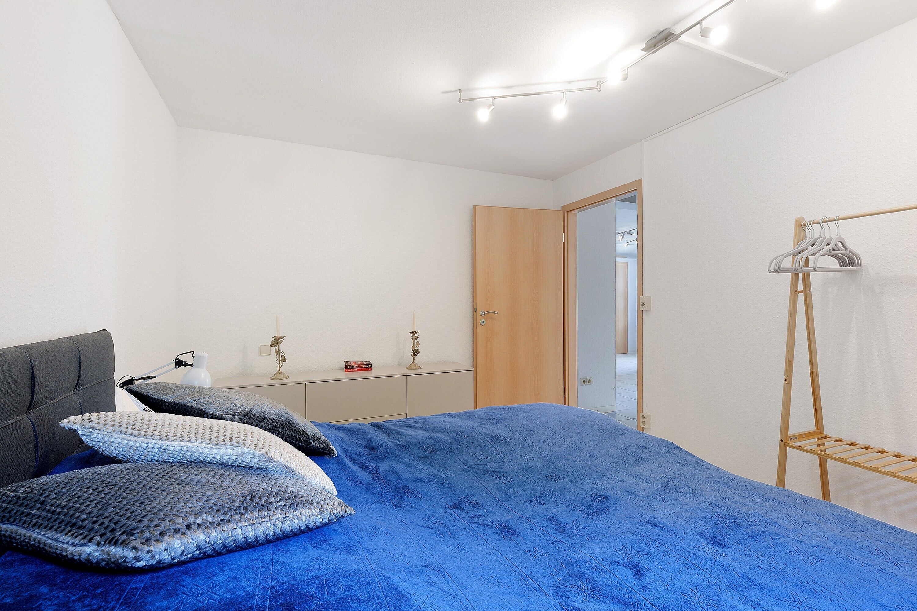 A bedroom with a bed, bedside table, lamp, and a wooden wardrobe.