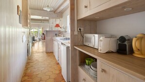 A kitchen with wooden cabinets, a microwave, a toaster, and a sink. - “Maison De Pays Églantine” with Private Terrace, Garden, and Wi-Fi (Sainte-Marie-de-Ré)