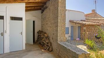 Un bâtiment rustique avec un mur en pierre, une porte en bois et une pile de bois de chauffage.