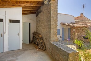 A rustic building with a stone wall, wooden door, and a stack of firewood. - “Maison De Pays Églantine” with Private Terrace, Garden, and Wi-Fi (Sainte-Marie-de-Ré)