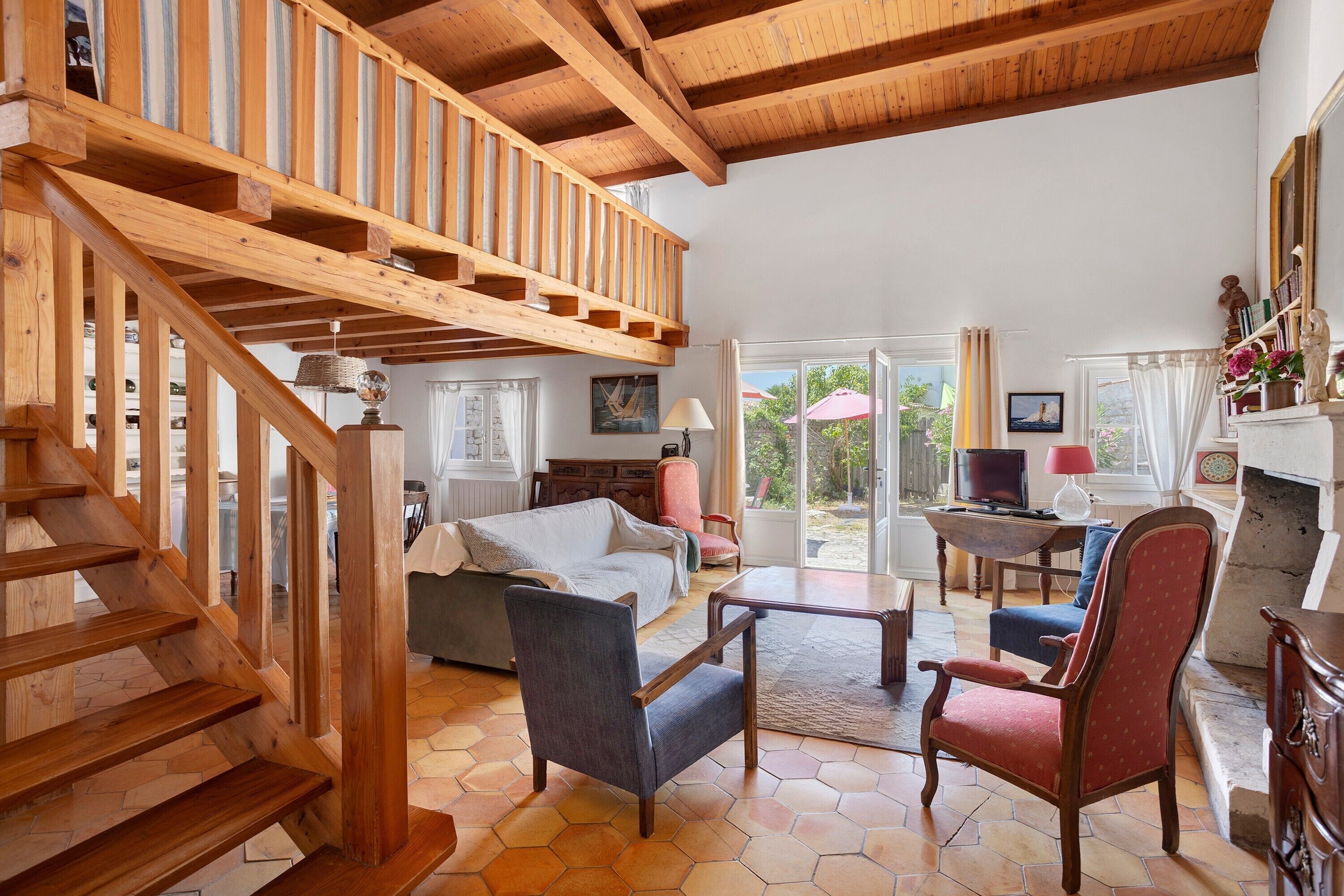 A spacious living area with a wooden staircase, a sofa, a coffee table, and a fireplace.