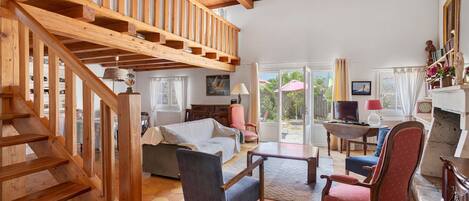 A spacious living area with a wooden staircase, a sofa, a coffee table, and a fireplace.