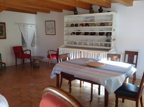 Un coin repas comprenant une table, des chaises, une bibliothèque et un tableau accroché au mur.