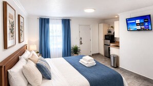 Une chambre d’hôtel équipée d’un lit, d’une télévision, d’une kitchenette et d’une salle de bain.