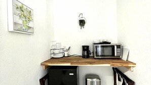 Une cuisine compacte équipée d’un four à micro-ondes, d’une machine à café et d’un petit réfrigérateur.