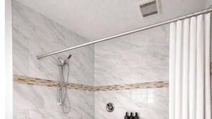 Une salle de bain moderne équipée d’une douche, de barres d’appui, de toilettes et d’un lavabo.