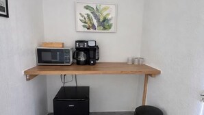Et tekøkken med mikrobølgeovn, kaffemaskine og lille køleskab.