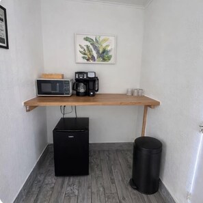 Eine Küchenzeile mit Mikrowelle, Kaffeemaschine und kleinem Kühlschrank.