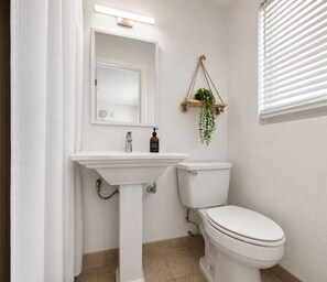 Ein Badezimmer mit einem weißen Waschbecken, Spiegel und WC.