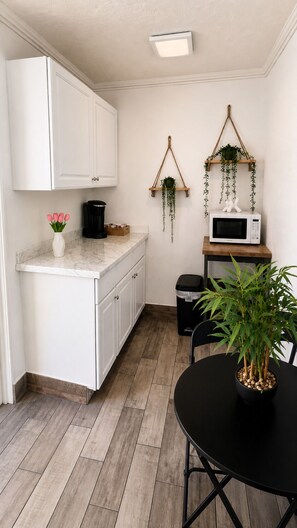 A compact kitchen with white cabinets, a microwave, a coffee maker, and hanging plants. - Clearwater Getaway w/ Pool • 3 Miles to Beach #4 (Clearwater)