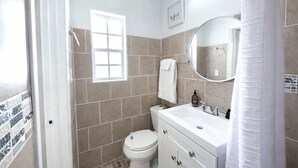 Un baño con inodoro, lavamanos con espejo y ventana.