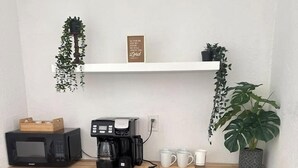 Uma cozinha compacta equipada com micro-ondas, cafeteira e pequena geladeira.