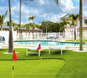 A swimming pool with a white fence, palm trees, and a building in the background. - 2B1B Stylish little house with Pool • Pets Ok #511 (Clearwater)