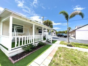 A single-story house with a porch, a lawn, and a street view. - 2B1B Stylish little house with Pool • Pets Ok #511 (Clearwater)