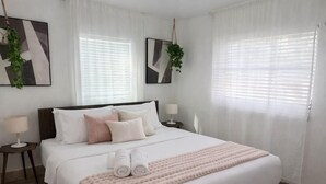A neatly arranged bedroom with a bed, bedside tables, and a hanging plant. - Studio 3 miles from the Beach, with pool #512 (Belleair)