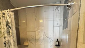 A shower with a curved showerhead, a soap dispenser, and a bottle on the floor. - Cozy apartment with pool in Clearwater #515 (Belleair)