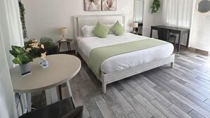Una habitación de hotel moderna con una cama, una mesa redonda, una silla, un escritorio y una planta en maceta.