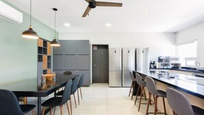 A modern kitchen with a central island, grey cabinets, and a ceiling fan. - 1G Casa Curie Coliving - Cama Matrimonial + Wifi (Monterrey)