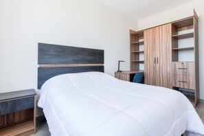 Ein Schlafzimmer mit Bett, Schreibtisch und Kleiderschrank.