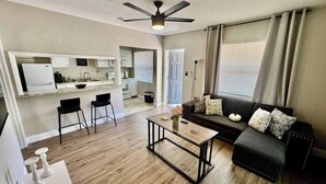 A living room with a sofa, coffee table, and a ceiling fan. - Beach Retreat: Modern 1-Bedroom • Pet Friendly (Clearwater)