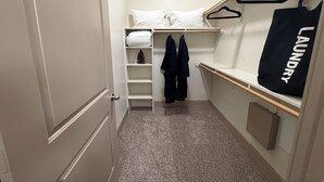 Ein kleines Zimmer mit einem Etagenbett, einer Wäschetasche und einem Kleiderschrank.