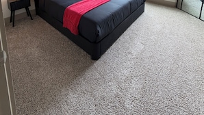 Ein Schlafzimmer mit einem Bett, zwei Nachttischen, einem Deckenventilator, zwei Fenstern und einem Spiegel.