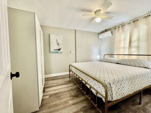 Ein Schlafzimmer mit einem Bett, einem Deckenventilator, einer Klimaanlage und einer Tür.