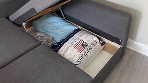 Een slaapbank met uitschuifbed, een decoratieve spiegel aan de muur, en een ingelijste foto.
