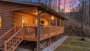 Eine Blockhütte mit einer Holzterrasse, einer Treppe und einem Veranda-Bereich.
