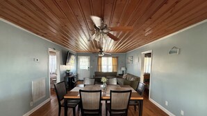 Zona pranzo con soffitto in legno, ventilatore a soffitto e tavolo da pranzo con sedie.