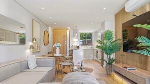 A modern living room with a sofa, a dining table, and a kitchen area in the background. - 2 Bed Beachfront Home with Panoramic Sea Views - Steps from the Beach (Cape Town)