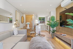 Ein modernes Wohnzimmer mit einer Couch, einem Esstisch und einer Küche im Hintergrund.