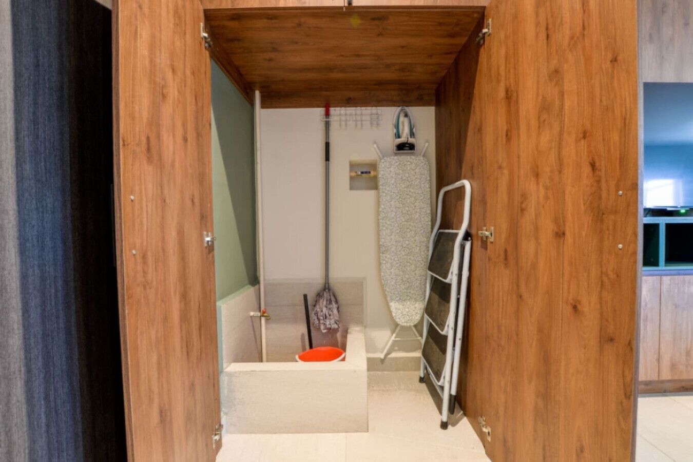 En trädør der fører til et badeværelse med bruser, tøjstativ og toilet.