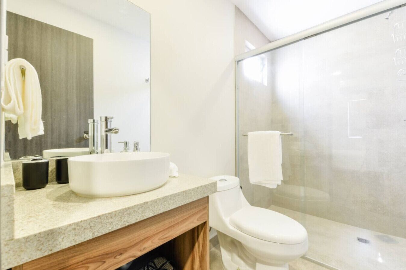 A modern bathroom with a large sink, mirror, and toilet.