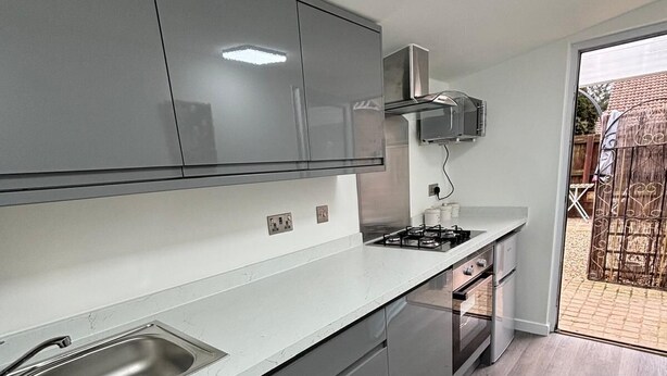 Una cocina moderna con armarios grises, un lavamanos de acero inoxidable y una estufa a gas.