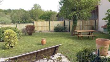 A backyard with a wooden fence, a wooden bench, and a large terracotta pot.