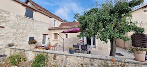 A stone building with a patio area featuring outdoor seating and potted plants. - Le clos du verger  (Eyraud-Crempse-Maurens)